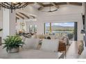 Bright open-concept living room with exposed beams, hardwood floors and a beautiful lake view at 3095 Heron Lakes Pkwy, Berthoud, CO 80513