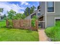 Home exterior featuring a wood fence, green lawn, and a covered entryway at 3381 Cripple Creek Trl # D14, Boulder, CO 80305