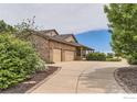Spacious driveway leading to a two-car garage with stone accents and covered side entrance at 6544 Saddleback Ave, Longmont, CO 80504