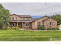 Charming two-story home with stone accents, covered front porch, and lush green lawn at 6544 Saddleback Ave, Longmont, CO 80504