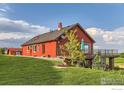 Charming home with a red exterior, featuring a balcony, lush green lawn, and picturesque surroundings at 8241 N Foothills Hwy, Boulder, CO 80302