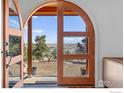 Beautiful view through an arched, multi-paned wooden door onto a patio area surrounded by lush foliage at 8543 Middle Fork Rd, Boulder, CO 80302
