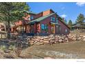 Charming home featuring a deck and a lush, green landscape with a beautiful stone retaining wall at 8543 Middle Fork Rd, Boulder, CO 80302