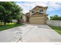 Well-manicured lawn and charming two-story home with stone accents and a two-car garage at 9673 Roadrunner Ave, Firestone, CO 80504