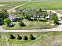 Aerial view of a residence featuring a well-maintained yard, mature trees, a windmill, and outbuildings at 0 Tbd E 112Th Ave, Bennett, CO 80102
