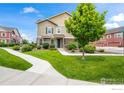 Charming two-story townhouse with a lush green lawn and sidewalk at 12724 Leyden St # E, Thornton, CO 80602
