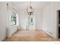 Elegant dining room featuring hardwood floors, a modern chandelier, and large windows with natural light at 1518 Hollyberry St, Berthoud, CO 80513