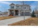 Charming two-story home with a covered front porch and an attached two-car garage with neutral paint colors at 1682 Dorothy Cir, Longmont, CO 80503