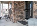 Close-up of the front porch featuring brick accents, seating and a covered entry with a security door at 1682 Dorothy Cir, Longmont, CO 80503