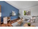 Inviting living room with blue accent wall, a comfortable sofa, and plenty of natural light from a large window at 2037 Spencer St, Longmont, CO 80501