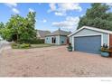 Charming exterior view of a blue house with a well-maintained lawn and a detached garage under a clear sky at 247 Tipple Pkwy, Frederick, CO 80530