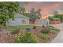 Charming blue home with a landscaped front yard featuring colorful flowers and lush greenery under a vibrant sky at 247 Tipple Pkwy, Frederick, CO 80530