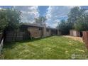 The expansive backyard features lush green grass, a shed, and a covered patio at 28 University Dr, Longmont, CO 80503
