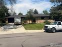 Single-story brick home, large driveway, beautiful mature landscaping, a trailer, and a white truck at 28 University Dr, Longmont, CO 80503