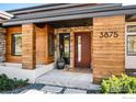 Modern entryway featuring a wooden door, stone accents, and professional landscaping at 3875 Cloverleaf Dr, Boulder, CO 80304