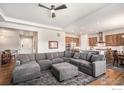 Open-concept living room with plush gray sectional, fireplace, kitchen view, and light-colored hardwood floors at 4600 Shady Path Ln, Castle Rock, CO 80104