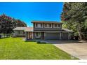 Charming two-story home boasts a well-manicured lawn and inviting red door at 5004 Fox Hill Dr, Longmont, CO 80504
