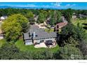 Aerial view of backyard, showcasing a patio and lush landscaping and mature trees at 5004 Fox Hill Dr, Longmont, CO 80504
