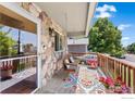 Cozy front porch with a charming swing, decorative pillows, vibrant flowers, and stone accents on the home's exterior at 602 S 9Th St, Berthoud, CO 80513