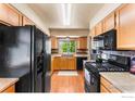 Efficient kitchen with wooden cabinets, black appliances, and a window view of outdoor greenery at 602 S 9Th St, Berthoud, CO 80513