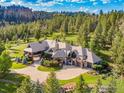 Stunning exterior elevation with beautiful stonework, a circular driveway, and lush landscaping at 6917 Timbers Dr, Evergreen, CO 80439