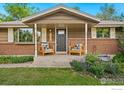Inviting covered front porch with comfortable seating and a welcoming entrance to this charming brick home at 7423 Saulsbury St, Arvada, CO 80003