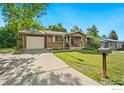 Lovely home boasting a well-kept lawn, inviting porch, and a paved driveway leading to the attached garage at 7423 Saulsbury St, Arvada, CO 80003