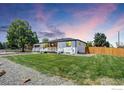 A well-manicured lawn surrounds a charming single story home with white brick and wood details at 7826 Joan Dr, Denver, CO 80221