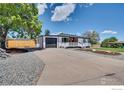 A white house is shown with black garage door, a large driveway and a beautiful lawn at 7826 Joan Dr, Denver, CO 80221