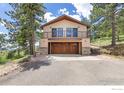 Two-story house featuring a garage and an upper-level balcony, surrounded by mature trees at 8323 Thunderhead Dr, Boulder, CO 80302