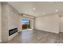 A spacious living room with a modern fireplace, light gray wood floors, neutral walls and sliding glass doors at 875 E 78Th Ave # 68, Denver, CO 80229