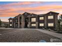 Apartment building with stone accents, balconies, and well-kept parking area at 875 E 78Th Ave # 72, Denver, CO 80229