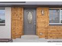 Close-up of the attractive front door framed by wood paneling and white brick at 9230 Aspen Dr, Thornton, CO 80229