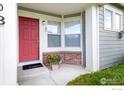Inviting front entrance with a vibrant red door, welcoming mat and charming flower pot at 13900 Lake Song Ln # 3, Broomfield, CO 80023