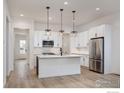 Bright kitchen with white cabinets, stainless steel appliances, an island, and modern pendant lighting at 1571 Poplar Dr, Erie, CO 80516