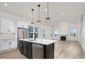 Open concept kitchen features an island, stainless steel appliances, and a view of the living room fireplace at 1571 Poplar Dr, Erie, CO 80516