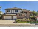 Two-story brick home featuring a three-car garage, manicured lawn, and professional landscaping at 16261 W Ellsworth Ave, Golden, CO 80401