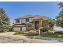 Two-story brick home with three-car garage, landscaping, and a lush green lawn on a clear day at 16261 W Ellsworth Ave, Golden, CO 80401
