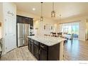 Open kitchen with granite island, stainless steel appliances, dark cabinets, and hardwood floors at 16527 Fairbanks N Rd, Platteville, CO 80651