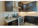 Modern kitchen with stainless steel appliances, granite countertops, and dark wood cabinetry at 16527 Fairbanks N Rd, Platteville, CO 80651