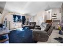 Comfortable living room with plush seating, large windows, and stairs leading to the upper level at 1687 Ensenada Way, Aurora, CO 80011