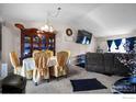 Open-concept living and dining area with vaulted ceilings, modern furniture, and large television at 1687 Ensenada Way, Aurora, CO 80011