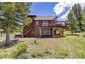 Exterior of rustic brown home featuring a deck, stone accents, and lush surrounding greenery at 173 Silver Cloud Ln, Boulder, CO 80302