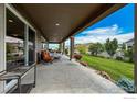 Inviting covered patio with lounge seating overlooks the manicured lawn and landscaping at 1910 High Plains Dr, Longmont, CO 80503