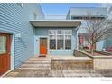Exterior view of modern condo featuring a wooden deck, colorful siding, and a bright orange door at 2018 Ionosphere St # 3, Longmont, CO 80504