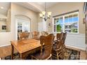 An elegant dining room featuring a large window for natural light, refined wall trim, and sophisticated chandelier at 2196 Winding Dr, Longmont, CO 80504