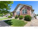 A well-maintained home with a brick facade, lush green lawn, and mature landscaping creates a welcoming curb appeal at 2196 Winding Dr, Longmont, CO 80504