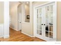 An inviting hallway with pristine hardwood flooring, decorative archways, and a stunning glass paneled french door at 2196 Winding Dr, Longmont, CO 80504