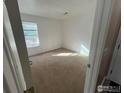 A bright bedroom is painted white with neutral carpeting and a window overlooking a residential street at 225 E 8Th Ave # B11, Longmont, CO 80504