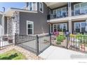 Townhouse exterior featuring outdoor patio space, landscaping, stone accents, and black metal fencing at 330 High Point Dr # 104, Longmont, CO 80504
